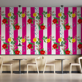 Coffee shop setting with chairs and tables. On the wall is a Tsonga inspired wallpaper. Wallpaper pattern of a colourful floral pattern of yellow flowers and red flowers with green leaves, on a background of pink and white vertical stripes.