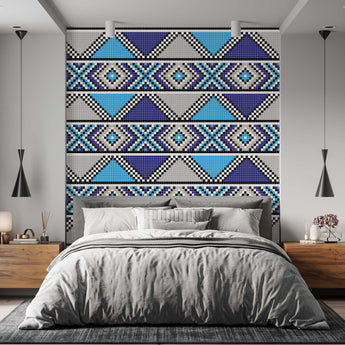 On a wall is a Zulu inspired wallpaper with a geometric repeat pattern of triangles and diamond shapes. Colours light blue, navy blue, black and white. Setting is a bedroom with a bed and wooden pedestals